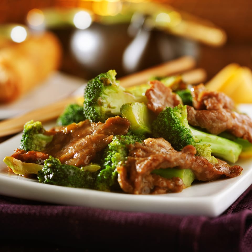 Chang Noi Thai's beef and broccoli stir-fry, with chopsticks and an egg roll in the background.