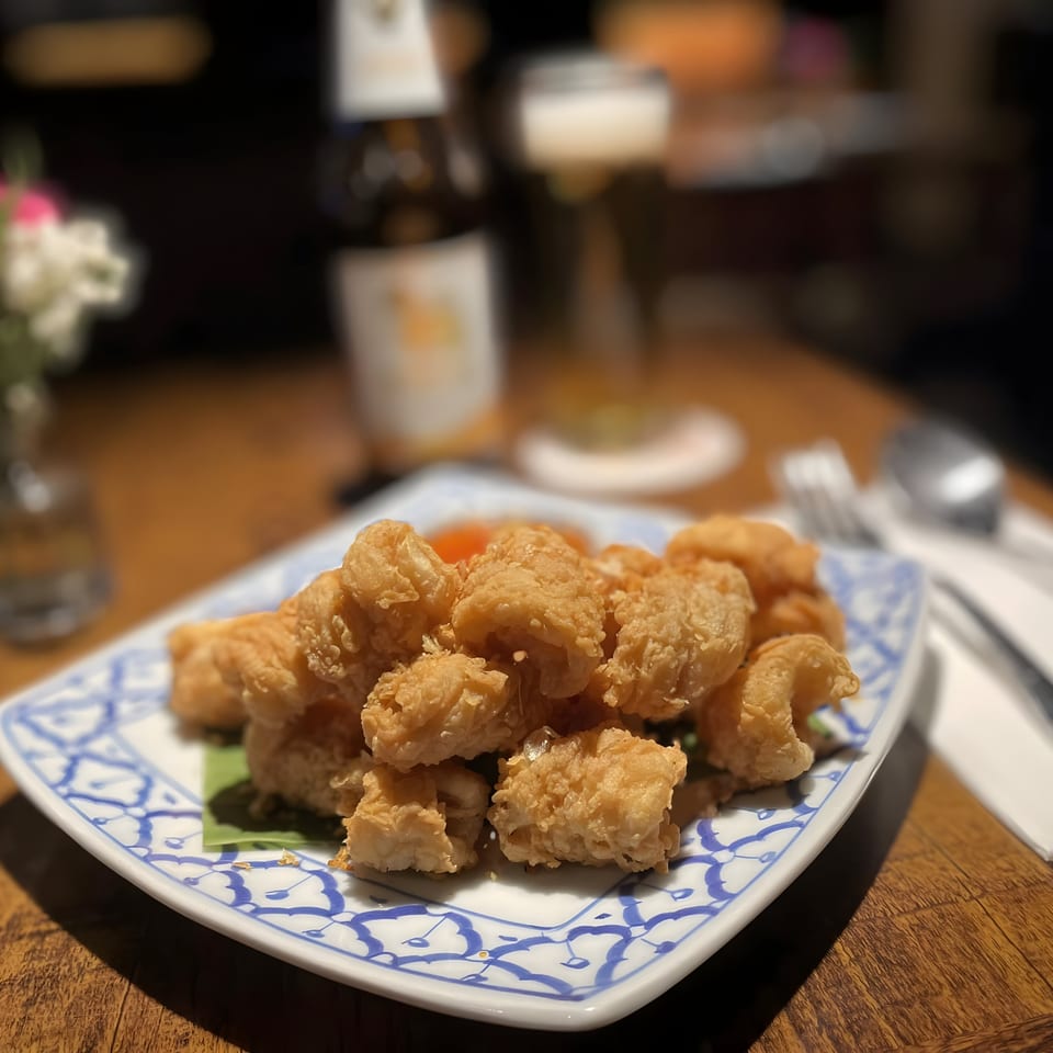 Crispy fried calamari on a blue and white patterned plate with a beer in the background.